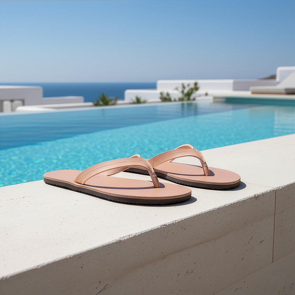 Pair of tan sandals on a ledge by a pool with ocean view